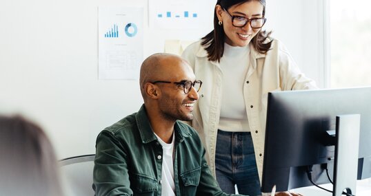 Web developers using a computer together in an office