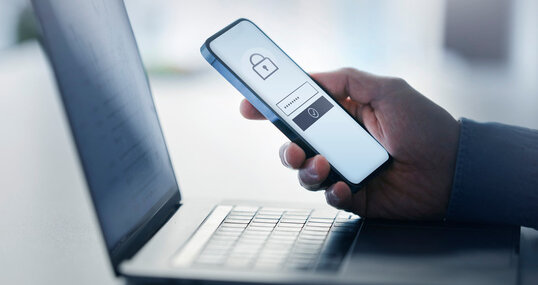 Man holding smart phone with data security on display at office