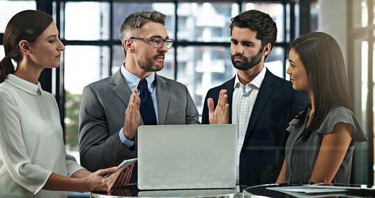 Four professionals in front of a laptop